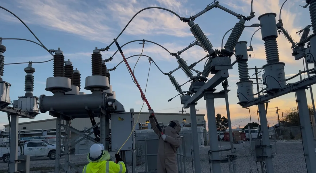 Crews working live substation bus at dusk during commissioning.