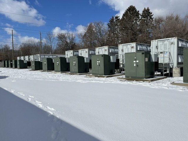 Battery storage enclosures operating in a snow-covered field.