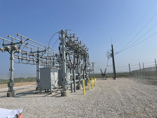 Engineer reviewing commissioning documentation at an energized substation.